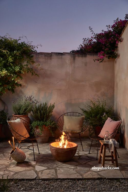 Small mediterranean garden ideas with a fire bowl patio seating area for warm evening outdoor living and cozy courtyard atmosphere