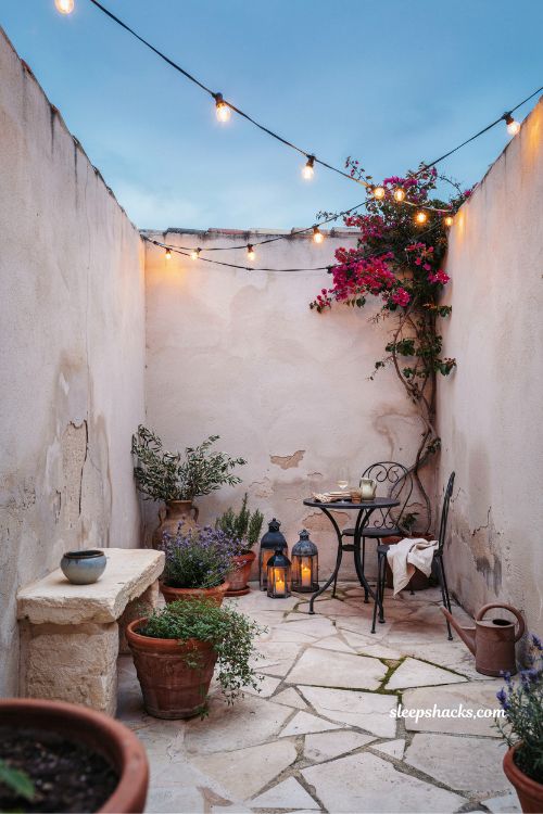 Small mediterranean garden ideas with string lights and lanterns creating a warm cozy evening courtyard glow 