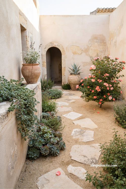 Small mediterranean garden ideas with succulents and rock rose in gravel beds for low water colorful courtyard design 
