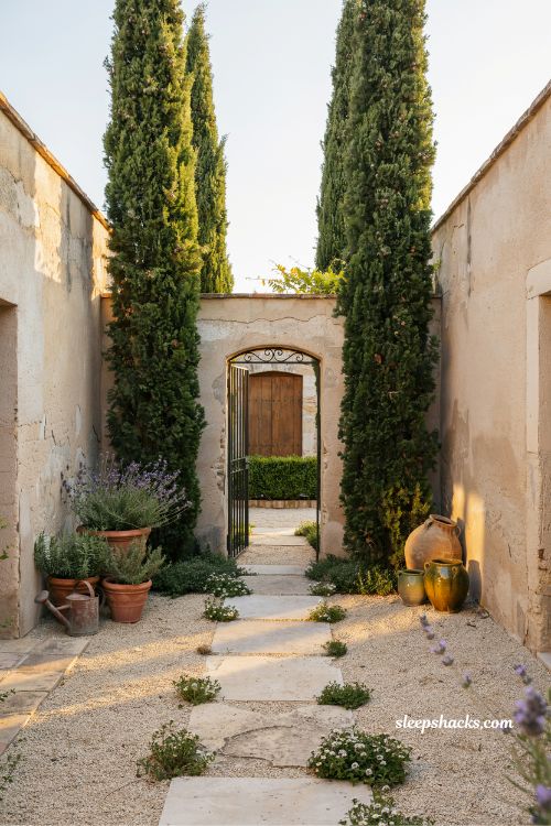 Small mediterranean garden ideas with tall italian cypress trees framing a courtyard entrance for vertical structure and elegance 