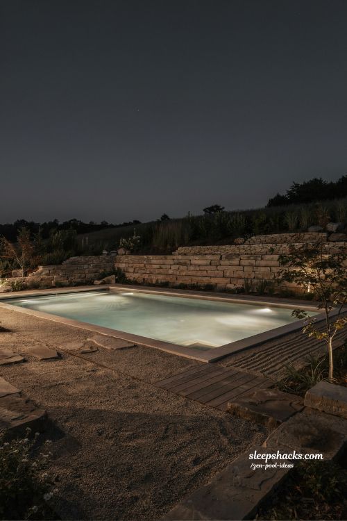 Small sloped backyard ideas with soft underwater pool lighting and zen night atmosphere