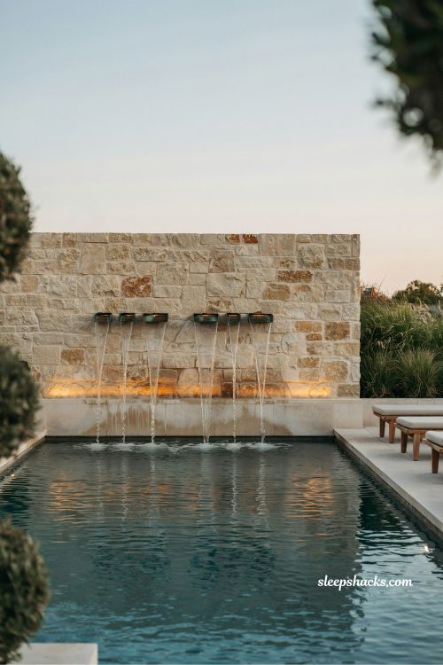 Stone veneer pool wall with copper scupper water feature design