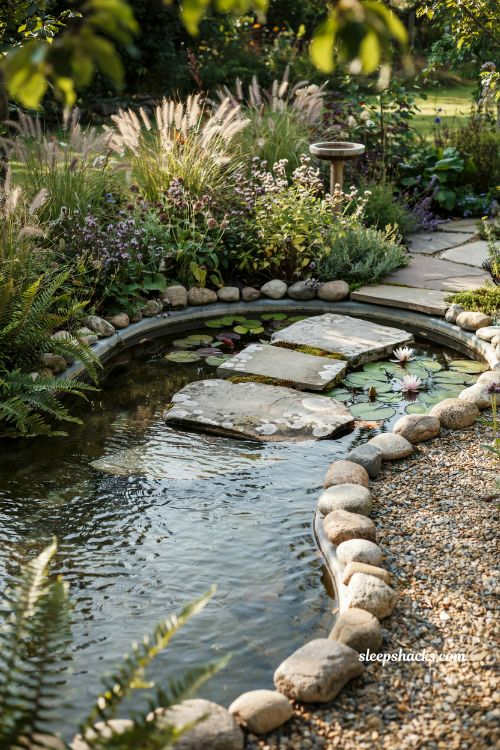 Wide-angle eye-level garden photography of a small inground pond with a stepping stone bridge crossing over it, a compact yet visually expansive backyard water feature designed to create depth and movement in a modest garden space, naturalistic cottage garden style with subtle woodland influences, soft moss greens, weathered stone grays, earthy browns, gentle water blues, and muted botanical tones, a shallow oval kidney-shaped pond lined with a hidden flexible liner and bordered with carefully placed river stones and natural edging, two to three flat stepping stones spanning across the water surface creating a simple crossing path, aquatic plants and lily pads floating gently around the stones, marginal ferns and low-growing groundcover softening the pond edges, gravel and natural stone accents blending into the surrounding landscape, layered planting beds with ornamental grasses and small flowering perennials adding softness and texture, soft morning sunlight filtering through nearby greenery and illuminating the water with crisp reflections and subtle ripples, even natural lighting that reveals every texture in sharp detail from stone to leaf to water surface, a calm and immersive atmosphere where the pond becomes a quiet focal point in the garden, soft colors that instantly create serenity and balance, aged natural textures that add warmth and depth, simple but intentional design details that make a small space feel larger and more thoughtfully composed, no people, no text, no watermarks, no blur, no bokeh, all surfaces in sharp focus, photorealistic, 4K resolution, editorial interior photography, Pinterest-worthy