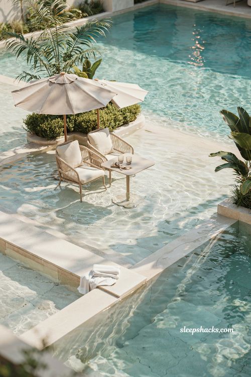 beach entry pool with umbrella and table setup in shallow ankle deep water social lounge
