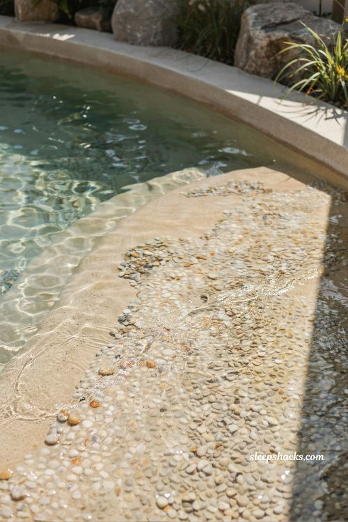pebble finish beach entry pool with natural textured shallow water flooring
