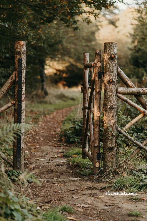 rustic cedar wood gate entrance ideas with natural tree trunk posts and handcrafted woodland fence design