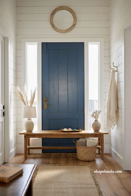 Beach house entryway ideas with white shiplap walls and bold blue front door