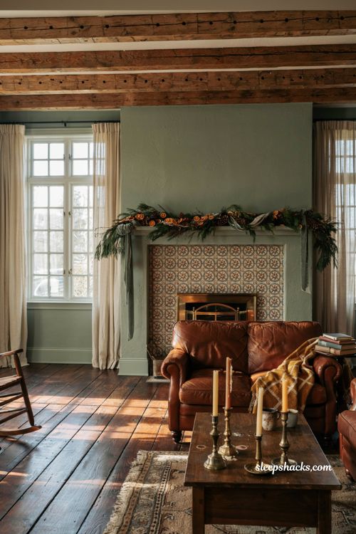 Christmas living room decor color scheme that complements existing sage green walls and warm cognac leather furniture