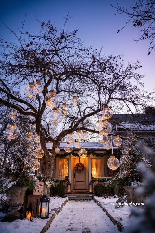 Christmas yard decorations ideas with oversized glowing ornaments hanging from a front yard tree