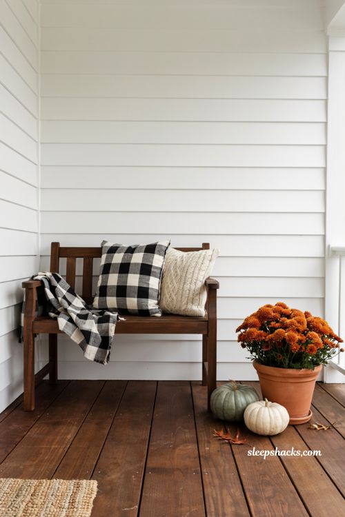 Classic outdoor fall decor ideas featuring black and white buffalo check blanket and pillows on a porch bench
