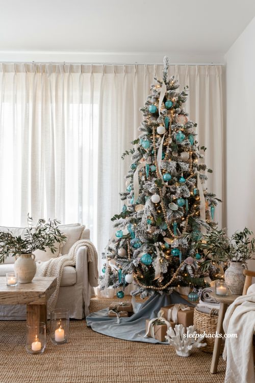 Coastal christmas living room with a flocked white tree and pale blue velvet tree skirt