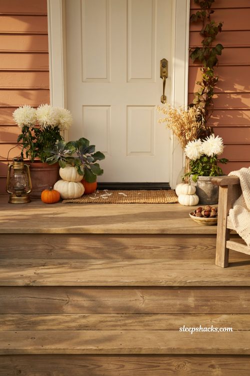 Cozy fall porch with layered white mums and pumpkins by the front door