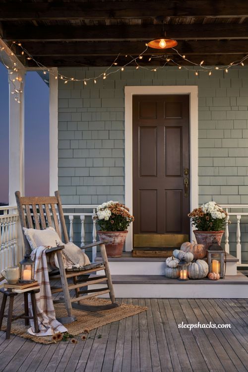 Cozy fall porch with warm string lights along the railing for cozy autumn evenings