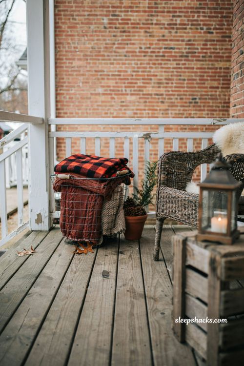Cozy outdoor fall blanket storage basket with plaid throws and pinecones for porch decor