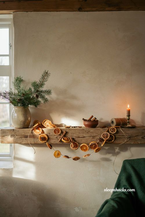 Diy dried orange garland christmas decor draped over a wooden fireplace mantel