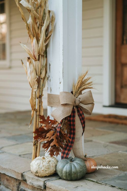 Dried corn stalks bundled against a porch post with burlap and plaid ribbon for fall decor