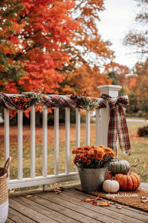 Fall front porch railing decor with plaid ribbon greenery berries and pumpkins