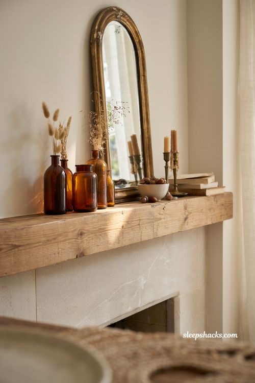 Fall mantle decor with amber glass bottles and vintage vases for a warm cozy fireplace styling