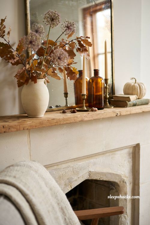 Fall mantle decor with preserved oak leaves and dried allium in a cozy farmhouse fireplace arrangement