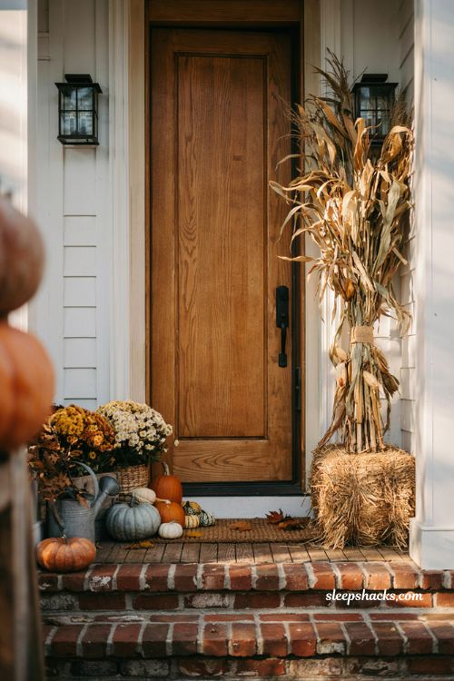 Fall porch decorating ideas with tall corn stalks hay bales and heirloom pumpkins