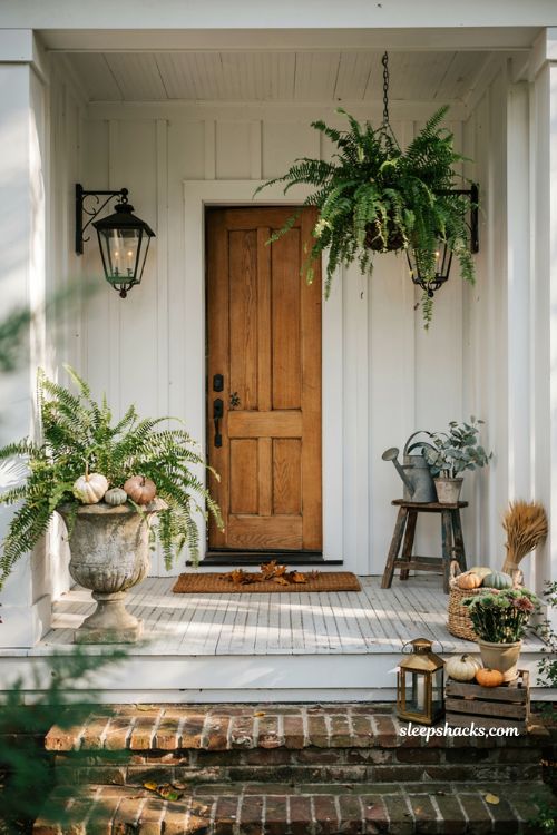 Fall porch decorating ideas with pumpkins nestled in lush summer ferns