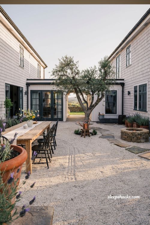 Farmhouse exterior courtyard layout ideas with pea gravel dining area stone fire pit and mature olive tree