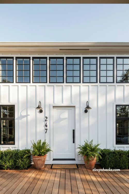 Farmhouse exterior ideas featuring white lap siding with black window frames and matching black porch lighting
