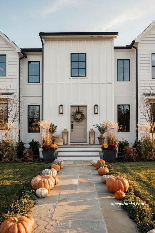 Front porch fall decorating ideas with a pumpkin lined walkway leading to a modern home