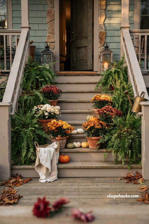 Front porch fall decorating ideas with layered ferns mums and pumpkins on stairway