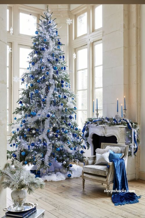 Glamorous blue and silver Christmas living room decor idea with flocked tree and cobalt blue ornaments