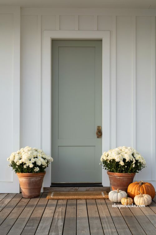 Minimal cozy fall porch with white mums and pumpkins by the front door