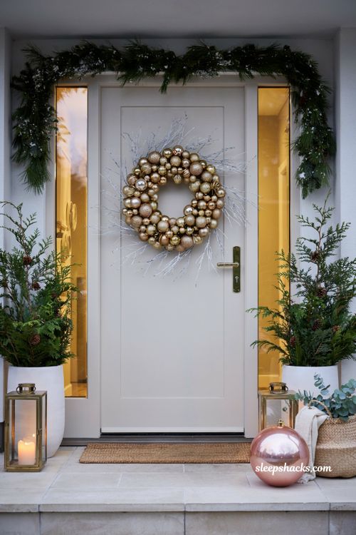 Modern Christmas front door ideas with gold ornament wreath and pink holiday decor