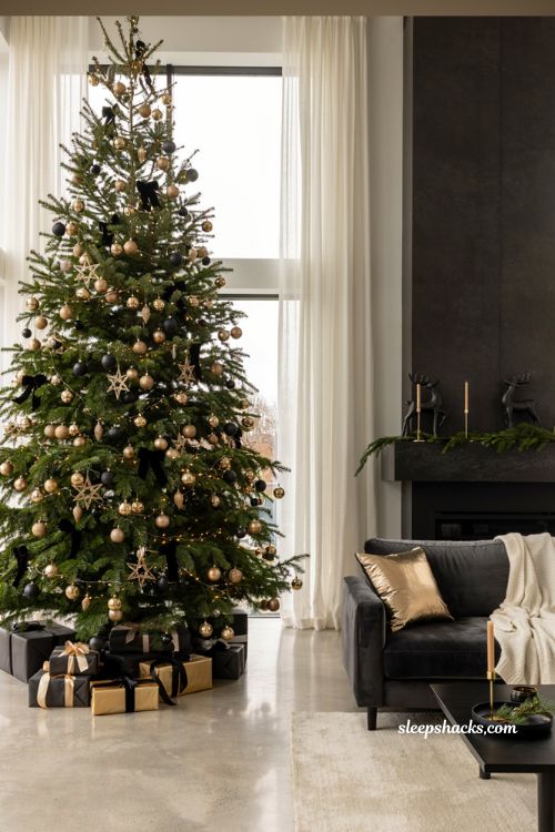 Modern black and gold Christmas living room decor idea with gold ornaments on a dark tree and black wrapping paper