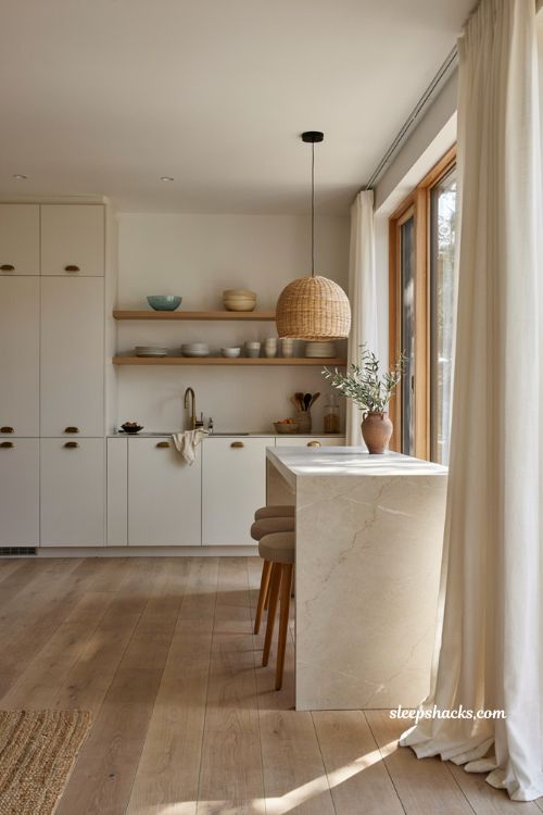 Modern coastal minimalist kitchen with white cabinets light oak shelves and woven pendant lighting