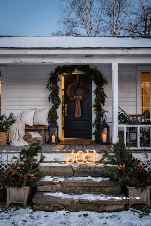 Outdoor christmas porch with glowing rope light joy sign and cozy farmhouse decor
