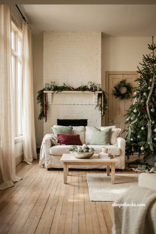 Sage green and cranberry Christmas living room color scheme idea with light wood floors and soft neutral decor