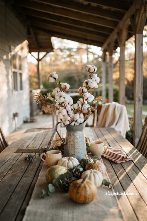 Simple fall patio table centerpiece with galvanized pitcher and mini pumpkins in cream and cinnamon tones