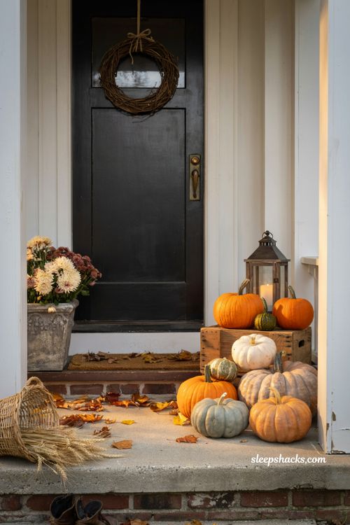 Simple fall porch decorating ideas with mixed orange white and green pumpkins on a cosy farmhouse entry