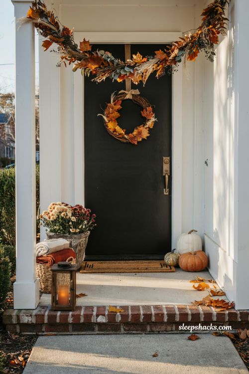 Small front porch fall decor ideas with autumn leaf garland wreath and cosy farmhouse entry