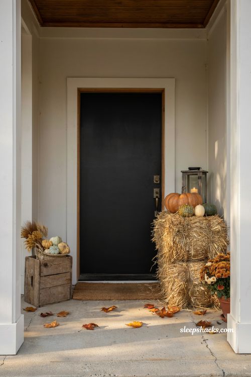 Small front porch fall decor ideas with stacked hay bales pumpkins lanterns and cosy farmhouse autumn styling