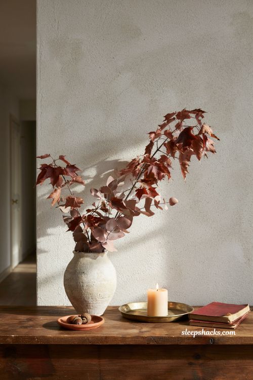 Tall faux fall branch arrangement in ceramic vase on entryway console table