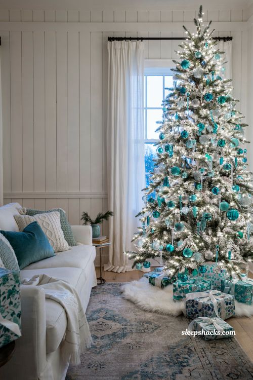 Teal and white Christmas living room decor idea with blue ornaments frosted tree and white throw pillows