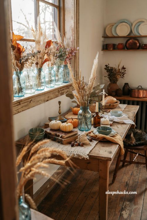 Vintage fall decor ideas with antique blue mason jars filled with autumn foliage in a cozy farmhouse kitchen