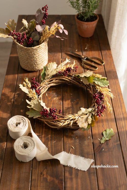 diy grapevine fall wreath with dried leaves and berries on a wooden craft workbench