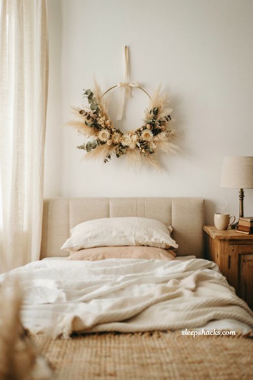 dried floral fall wreath hanging above a cozy bed with linen bedding