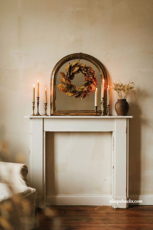 fall wreath hung over a gilded mantel mirror in a cozy living room