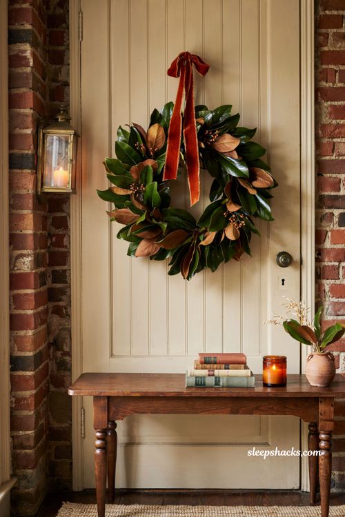 magnolia leaf fall wreath with rust velvet ribbon hanging on a classic front door