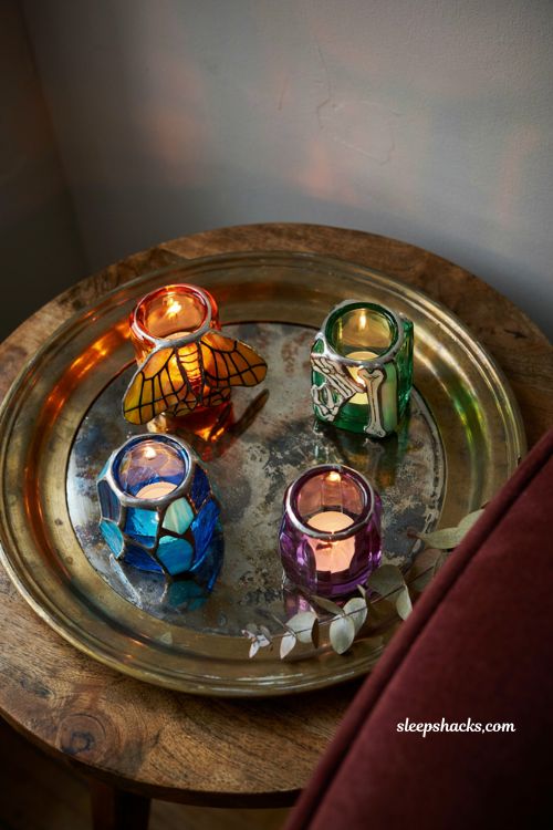 strained glass halloween votive candle holders casting colorful light on a cozy side table