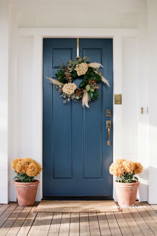 textured autumn wreath hanging on a navy blue front door for elegant fall curb appeal