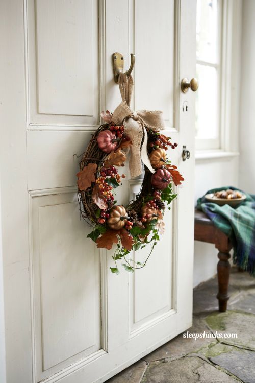 traditional autumn grapevine wreath with dried pumpkins berries and leaves hanging on a white front door